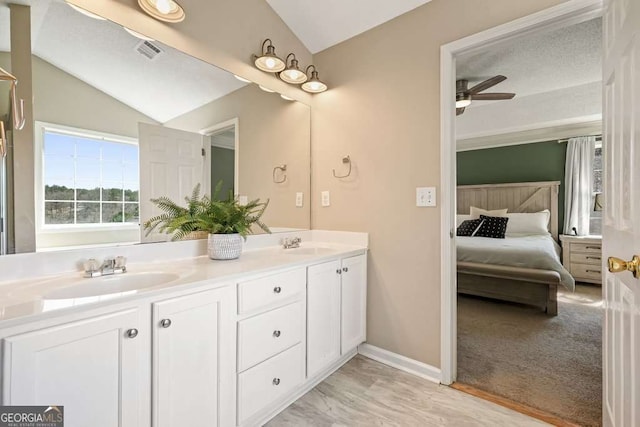 full bath with double vanity, visible vents, ensuite bathroom, vaulted ceiling, and a sink