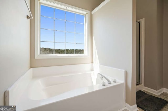 bathroom with a shower with door, baseboards, and a bath