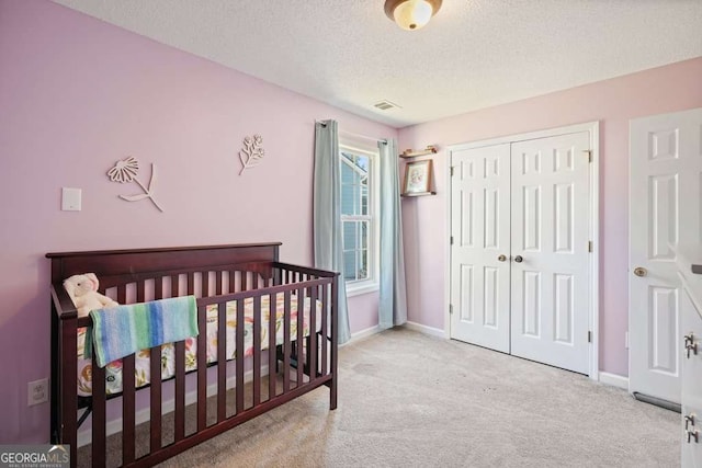 bedroom featuring a closet, light carpet, a textured ceiling, and baseboards