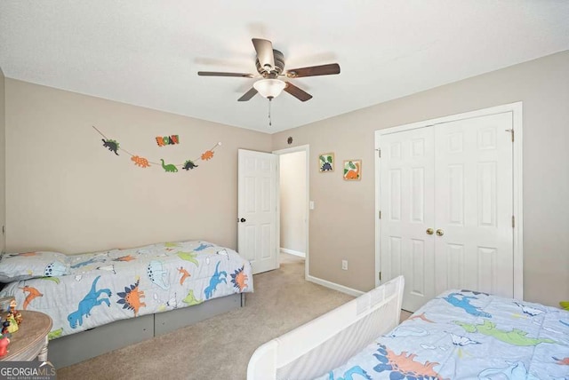 bedroom featuring a ceiling fan, a closet, light colored carpet, and baseboards