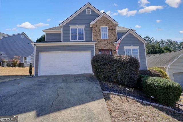 traditional-style home featuring a garage, concrete driveway, central AC unit, and brick siding