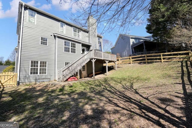 rear view of property with a deck, fence private yard, a chimney, and stairway