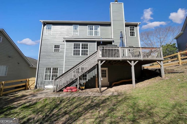 back of property with fence, a chimney, a wooden deck, and stairs