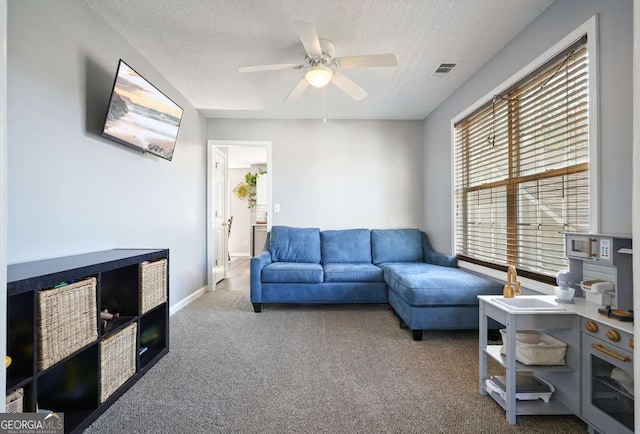 living room with a ceiling fan, carpet, visible vents, and a textured ceiling