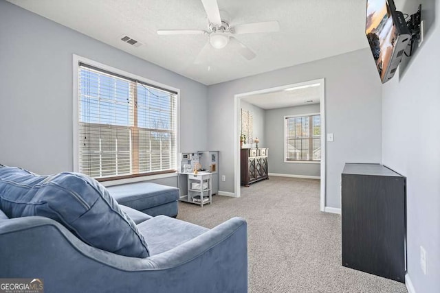 living room with visible vents, a ceiling fan, light carpet, a textured ceiling, and baseboards