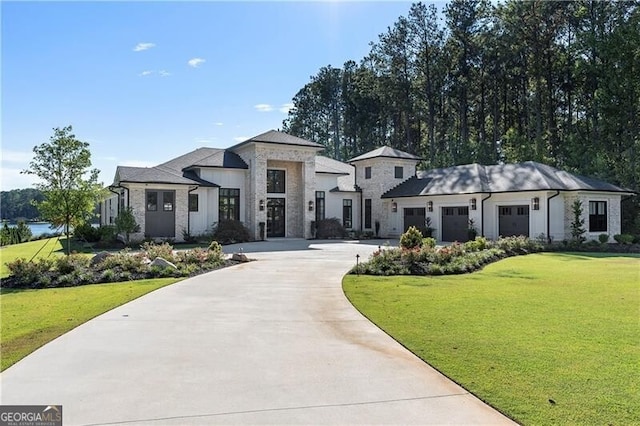 view of front of home featuring an attached garage, concrete driveway, stone siding, and a front yard