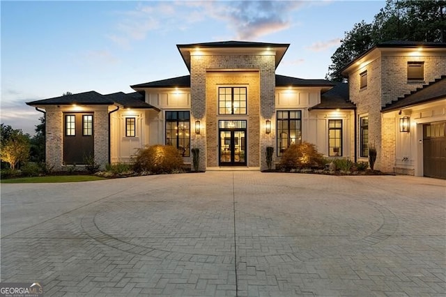 prairie-style house featuring french doors, decorative driveway, and brick siding