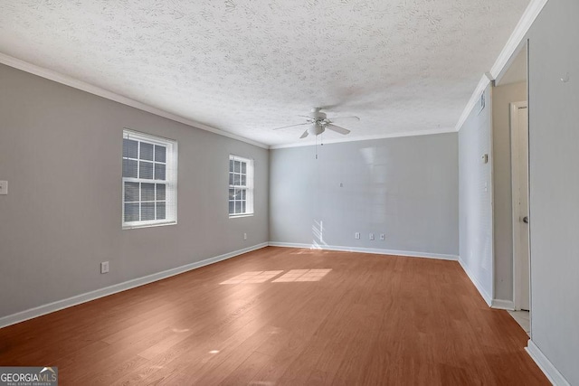 empty room featuring ceiling fan, crown molding, baseboards, and wood finished floors