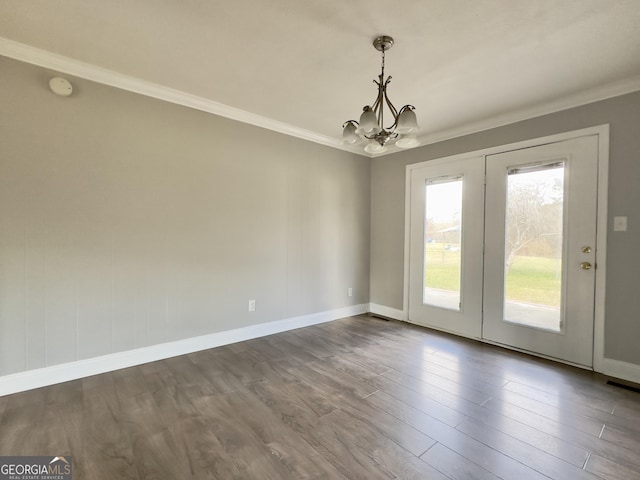 spare room featuring a chandelier, crown molding, baseboards, and wood finished floors