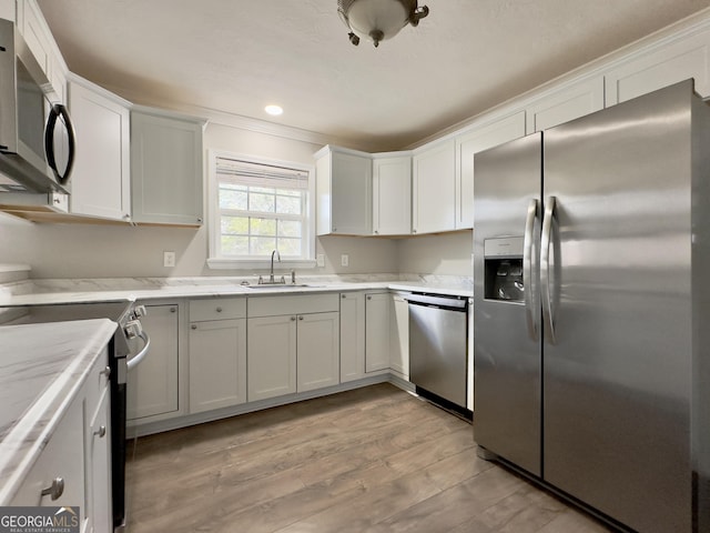 kitchen with appliances with stainless steel finishes, white cabinets, and a sink