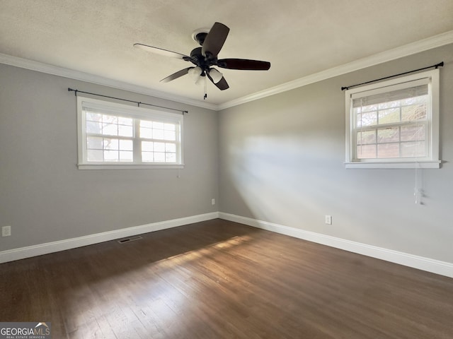 spare room with dark wood-style floors, crown molding, and baseboards