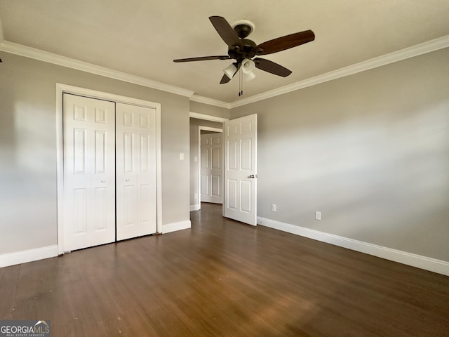 unfurnished bedroom featuring baseboards, dark wood-type flooring, a closet, and crown molding