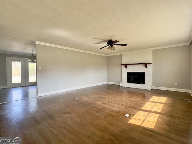 unfurnished living room with baseboards, dark wood-style flooring, a textured ceiling, a fireplace, and ceiling fan with notable chandelier