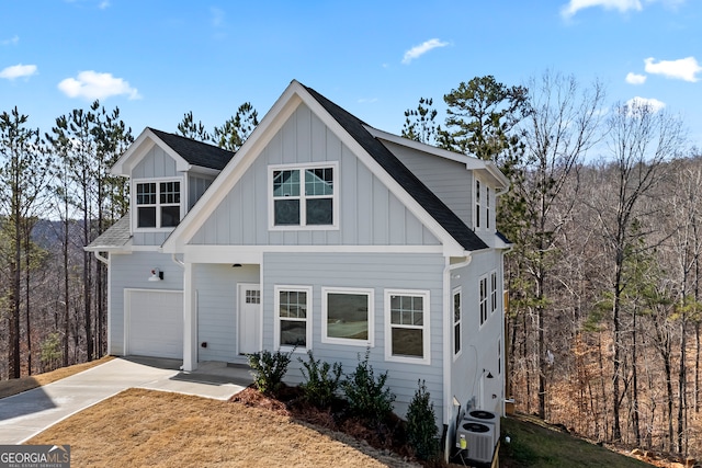 view of front of property with a garage, concrete driveway, roof with shingles, central air condition unit, and board and batten siding