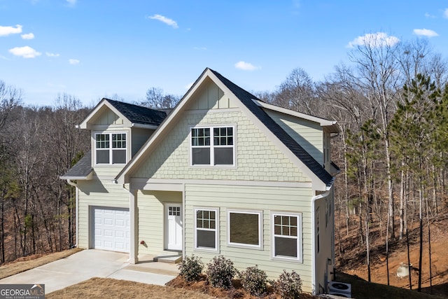 view of front of house with a garage, driveway, and a shingled roof