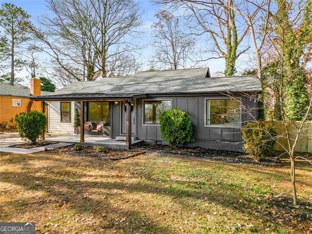 rear view of house featuring board and batten siding, a yard, a patio, and fence