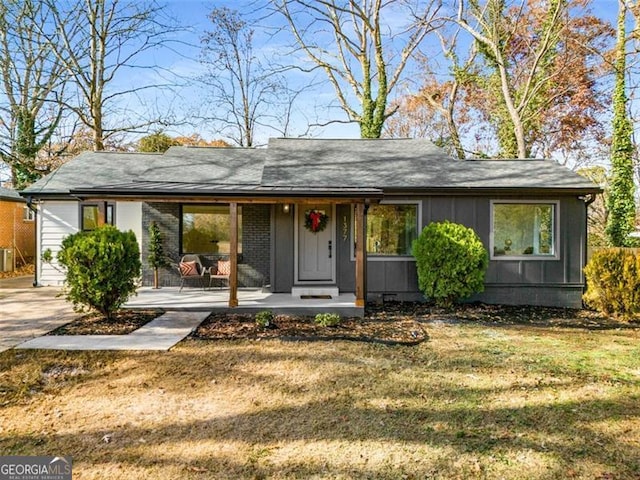 view of front facade featuring a porch, a front yard, brick siding, and board and batten siding