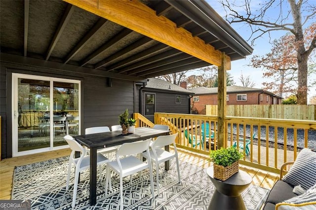 wooden terrace with outdoor dining space and fence