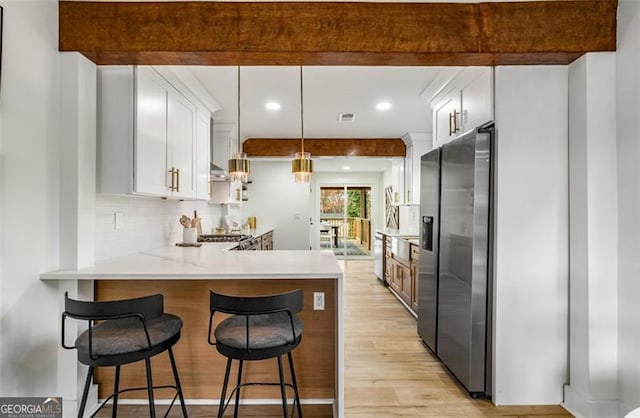 kitchen featuring appliances with stainless steel finishes, decorative light fixtures, a peninsula, light countertops, and white cabinetry