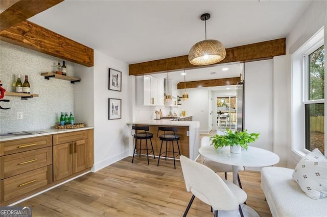 interior space with light wood-style floors, light countertops, open shelves, brown cabinetry, and pendant lighting