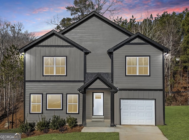 view of front of home with board and batten siding, a front lawn, driveway, and a garage