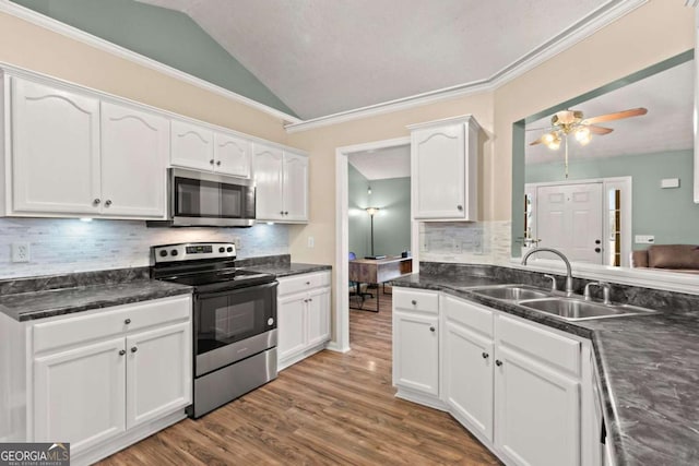 kitchen featuring stainless steel appliances, white cabinetry, vaulted ceiling, a sink, and wood finished floors