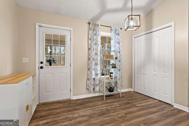 interior space with dark wood-type flooring, a textured ceiling, and baseboards