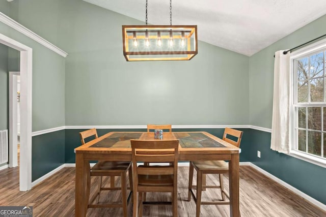 dining room featuring vaulted ceiling, baseboards, and wood finished floors