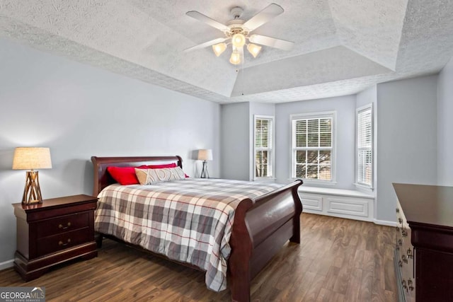 bedroom featuring baseboards, a textured ceiling, a tray ceiling, and dark wood-style flooring