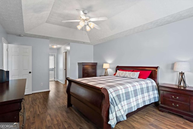 bedroom featuring a textured ceiling, a ceiling fan, baseboards, dark wood-style floors, and a raised ceiling