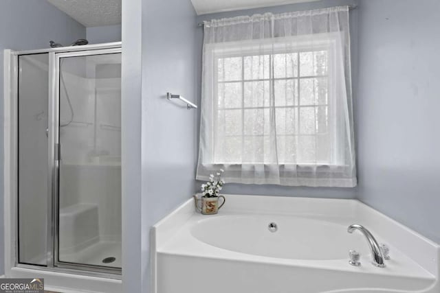 bathroom with a bath, a shower stall, and a textured ceiling