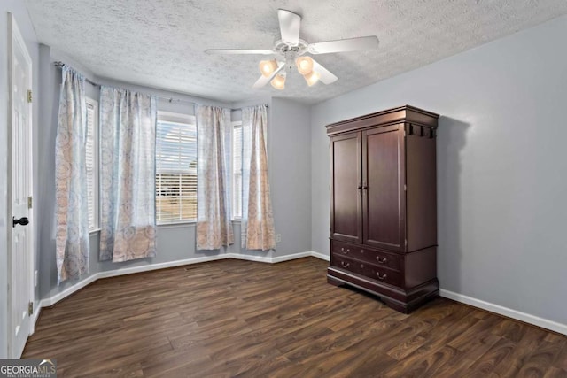 unfurnished bedroom with dark wood finished floors, a textured ceiling, and baseboards