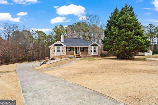 view of front of home with covered porch, stone siding, a chimney, and driveway