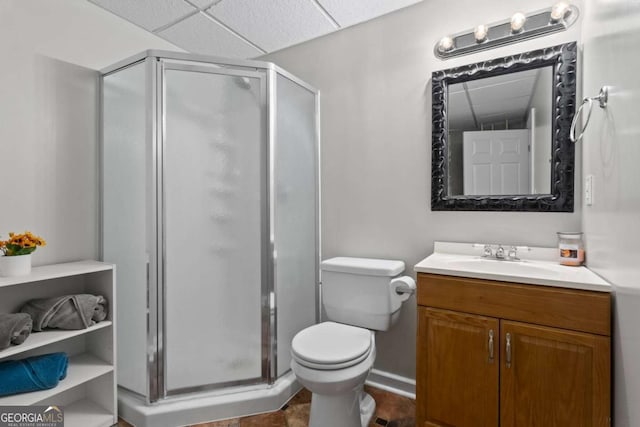 full bathroom with toilet, a stall shower, a drop ceiling, and vanity