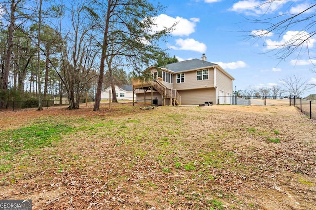 rear view of house with a garage, a fenced backyard, a chimney, stairs, and a wooden deck