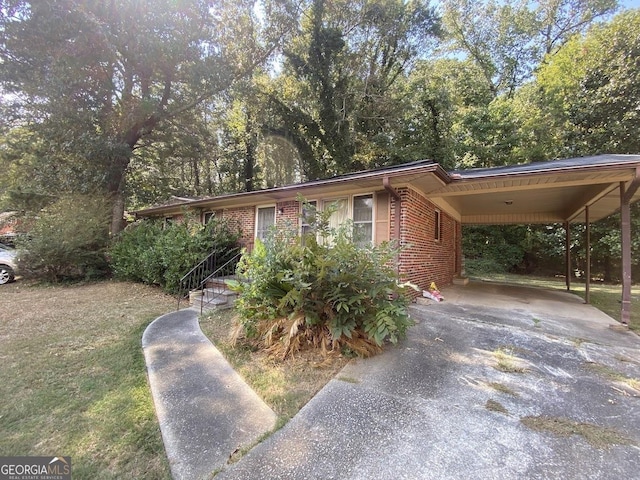 view of front of home with driveway, brick siding, and an attached carport