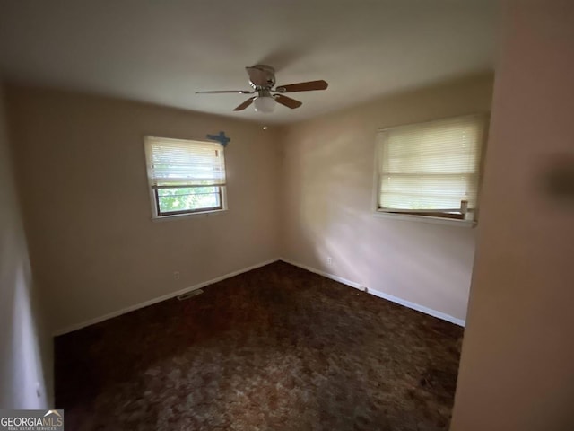 carpeted spare room featuring a ceiling fan, visible vents, and baseboards