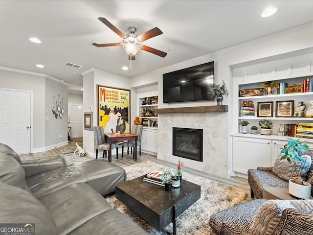 living area featuring visible vents, built in features, light wood-style flooring, ornamental molding, and recessed lighting