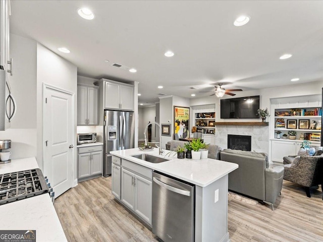 kitchen featuring stainless steel appliances, light wood-type flooring, a sink, and gray cabinetry