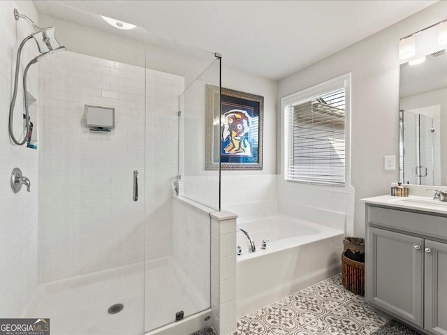 full bathroom featuring a stall shower, tile patterned flooring, a garden tub, and vanity