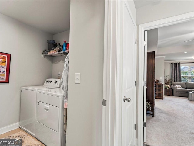 laundry area with light tile patterned flooring, light carpet, laundry area, baseboards, and washing machine and clothes dryer