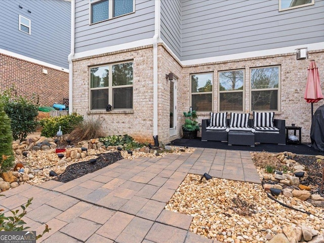 doorway to property featuring brick siding, a patio area, and an outdoor living space