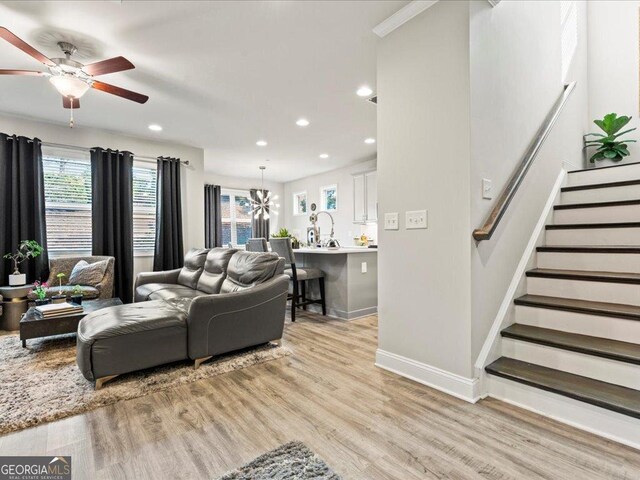 living room featuring stairs, baseboards, a wealth of natural light, and light wood-style floors