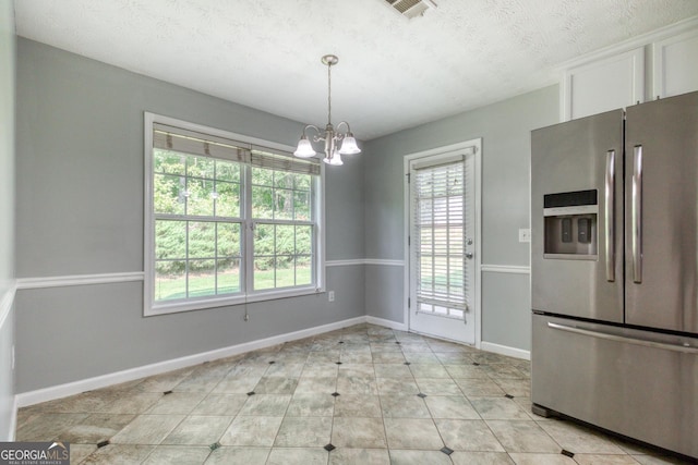 unfurnished dining area with light tile patterned floors, visible vents, baseboards, an inviting chandelier, and a textured ceiling