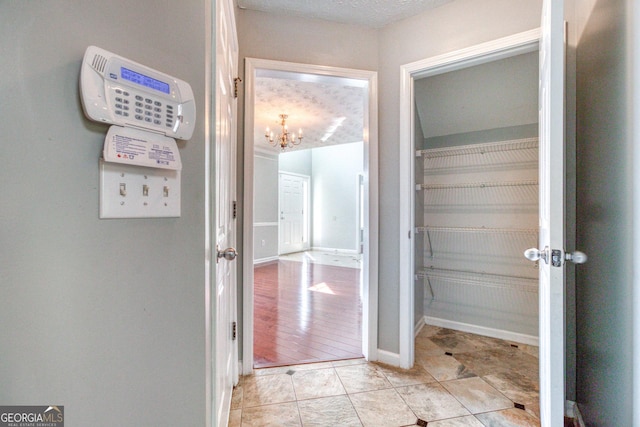 doorway featuring an inviting chandelier, baseboards, a textured ceiling, and light tile patterned flooring