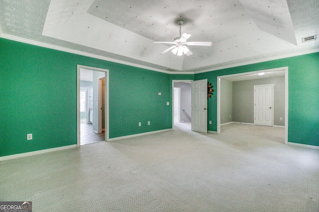 unfurnished bedroom with crown molding, a raised ceiling, and light colored carpet