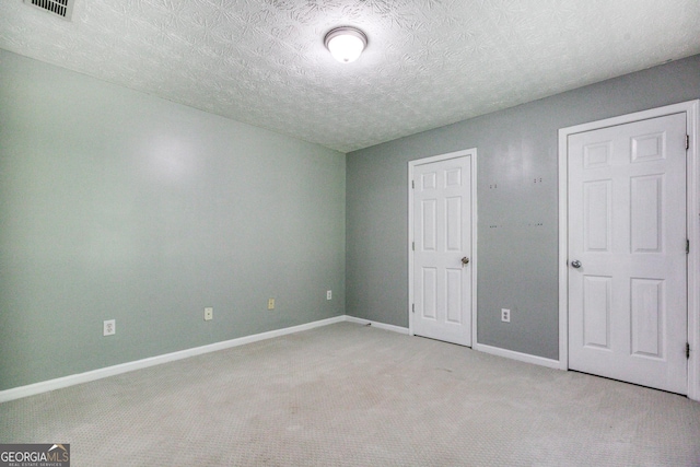 unfurnished bedroom with light carpet, visible vents, baseboards, and a textured ceiling