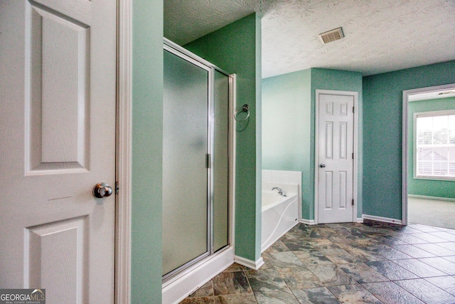 bathroom featuring a garden tub, visible vents, a stall shower, a textured ceiling, and baseboards