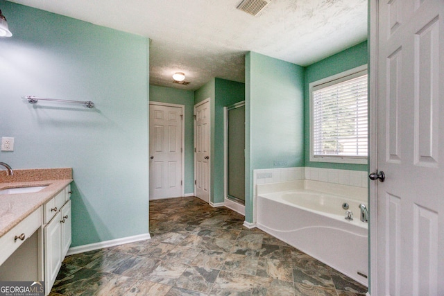 bathroom featuring visible vents, vanity, a textured ceiling, baseboards, and a bath