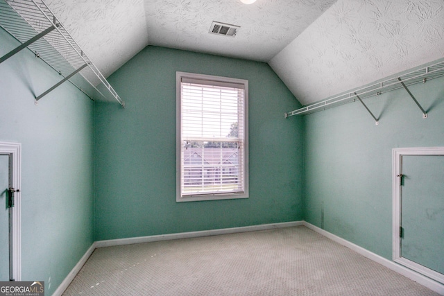 spacious closet featuring vaulted ceiling, carpet floors, and visible vents